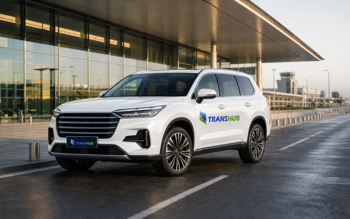 Illustrative white TransHub-branded premium SUV outside an airport terminal